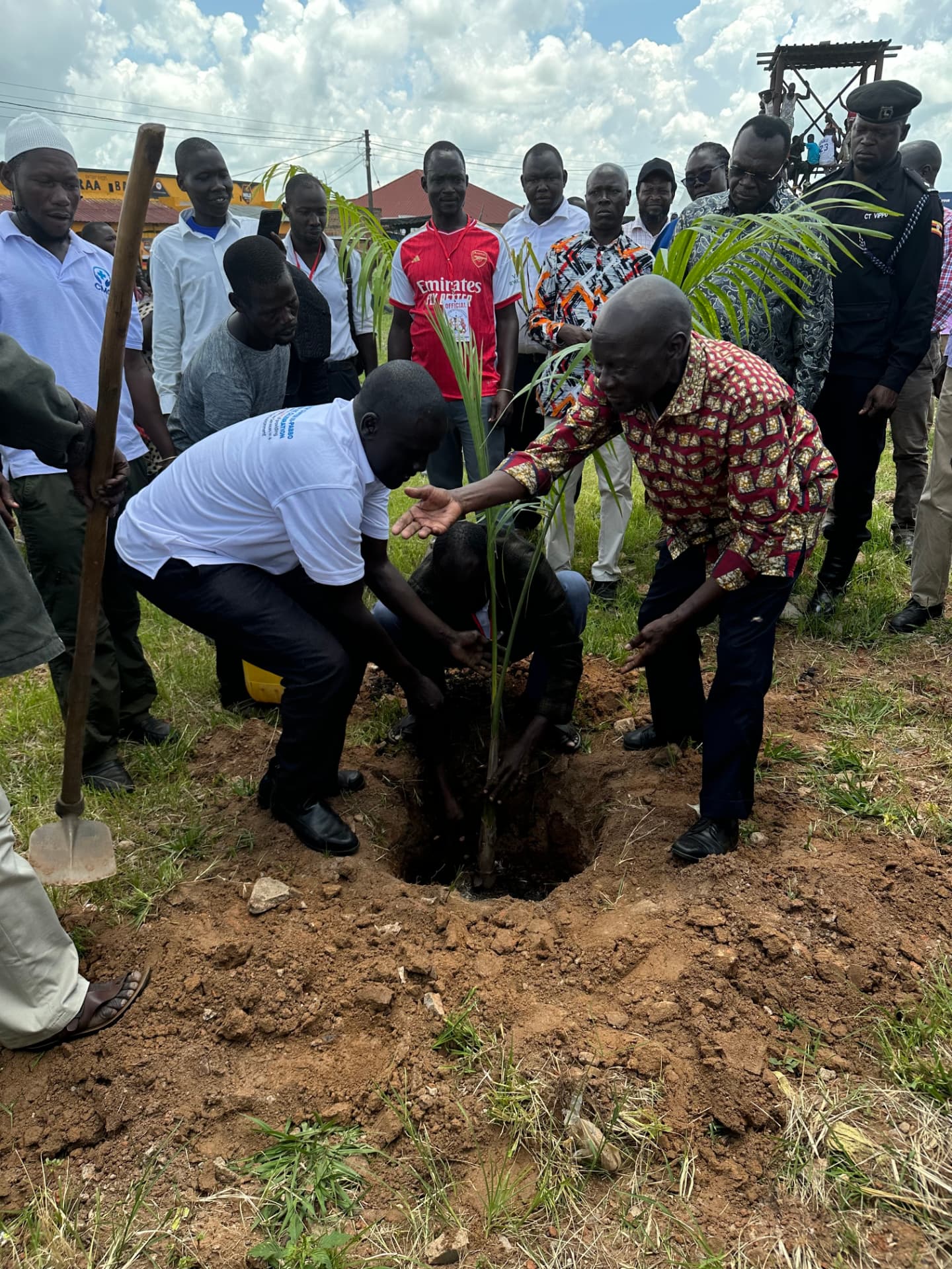 Olara Otunnu planting a tree with community members